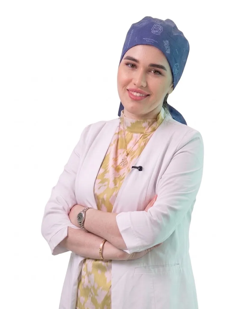 A professional and smiling female specialist at Helia Clinic, wearing a white lab coat and blue surgical cap.